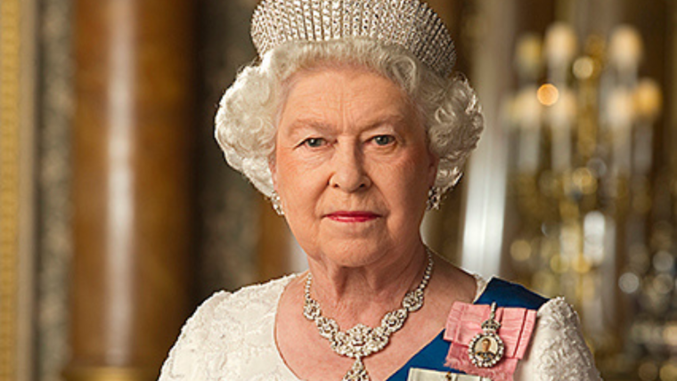 Photo of Queen Elizabeth wearing a crown and white formal dress with blue sash